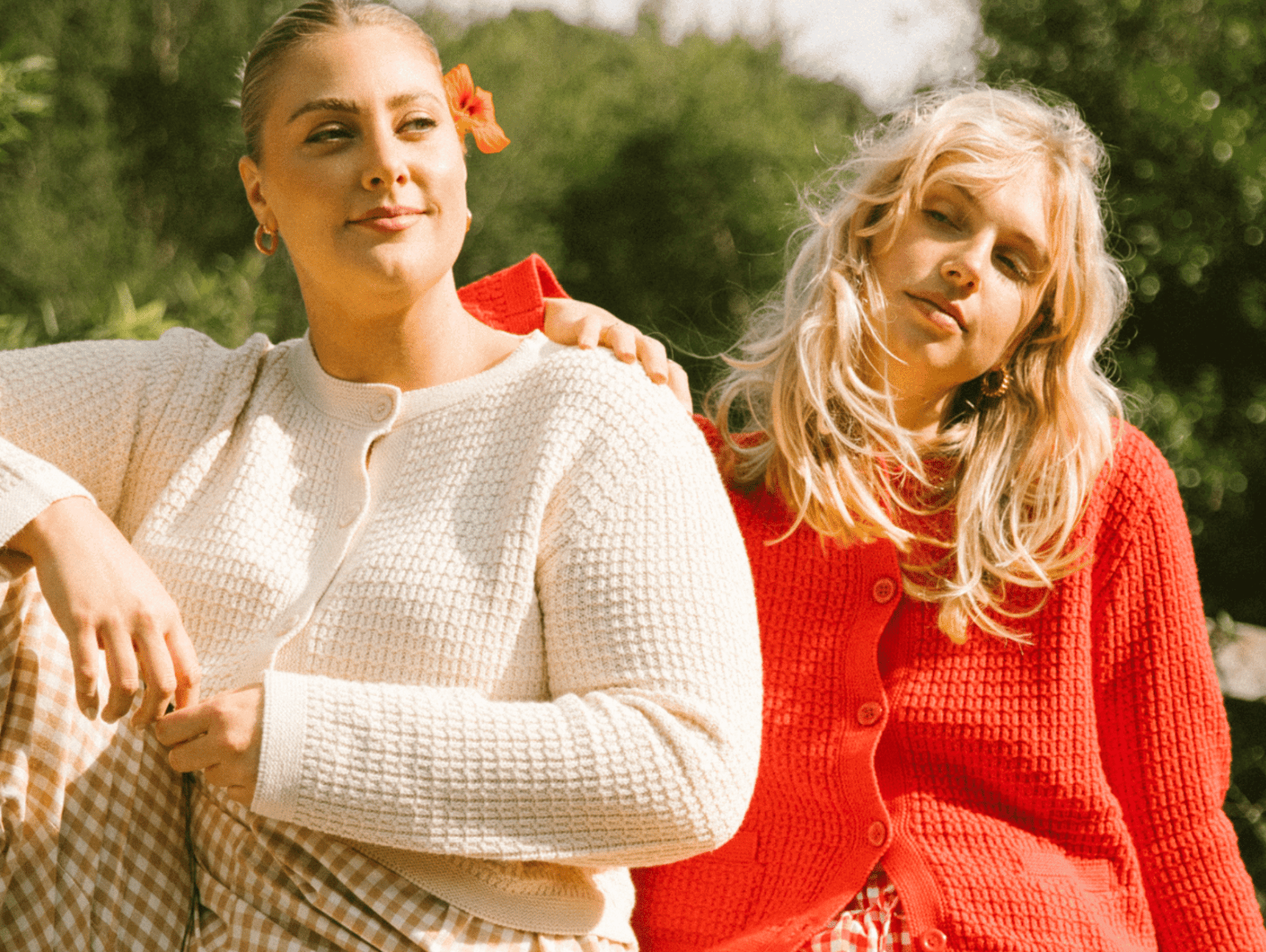 Two women sitting next to each other on a bed outside, wearing printed pyjamas