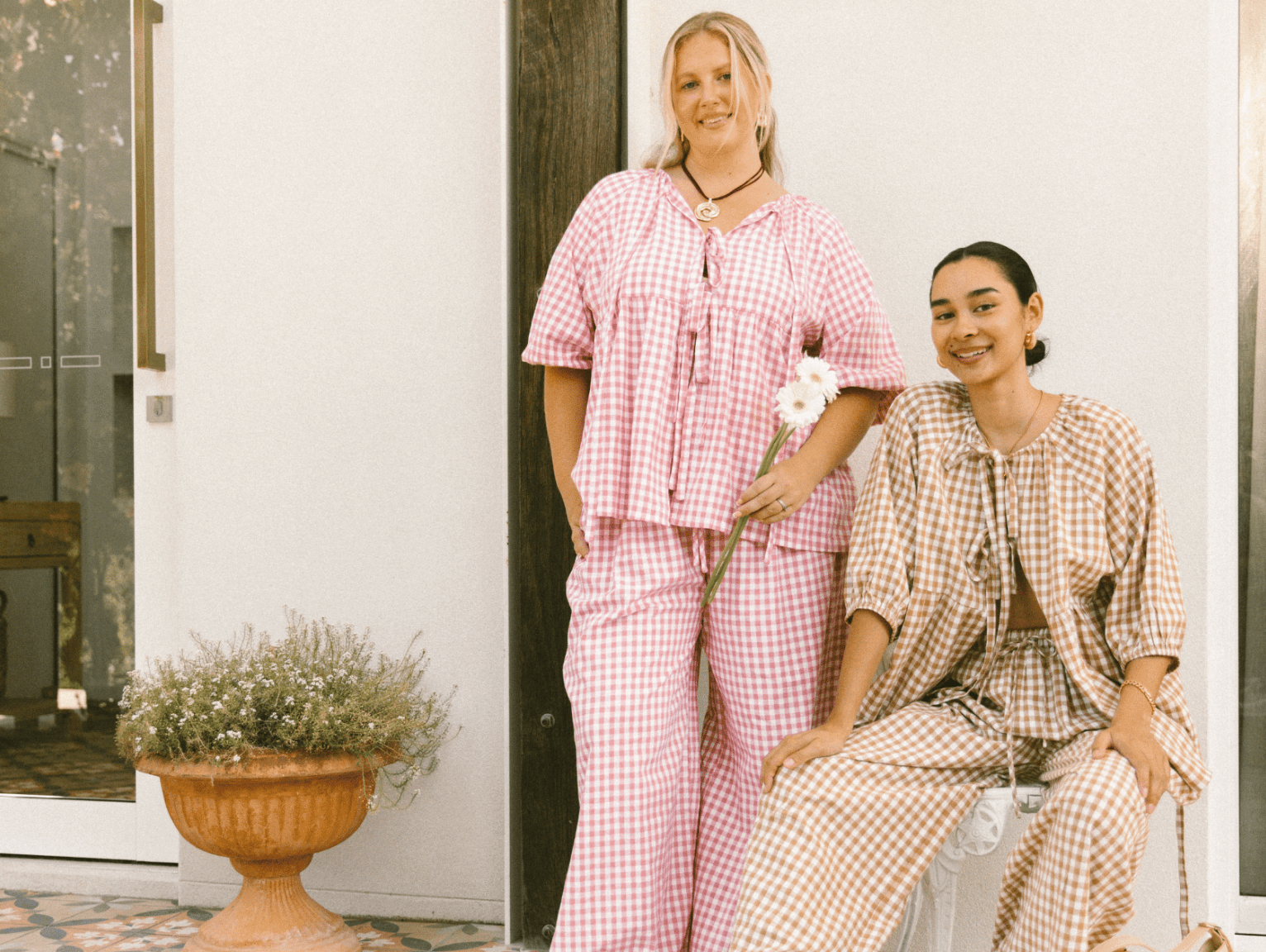 Three women wearing linen printed sets, relaxed sitting on stairs outside in a fashionable manner