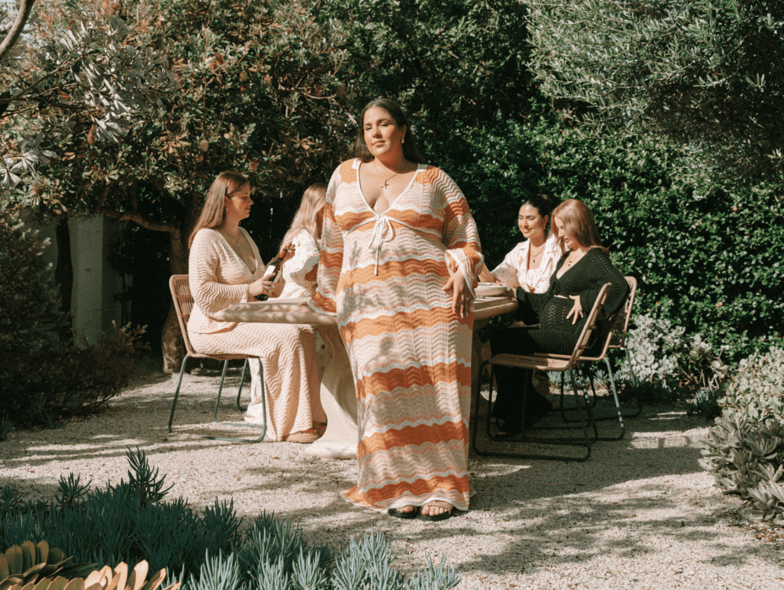 Four women wearing floral and floaty outfits in a garden