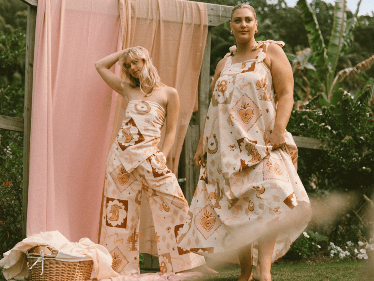 Two women standing next to each other with their hands in each others jean pockets. It's a close up of two pairs of jeans, blue and black.