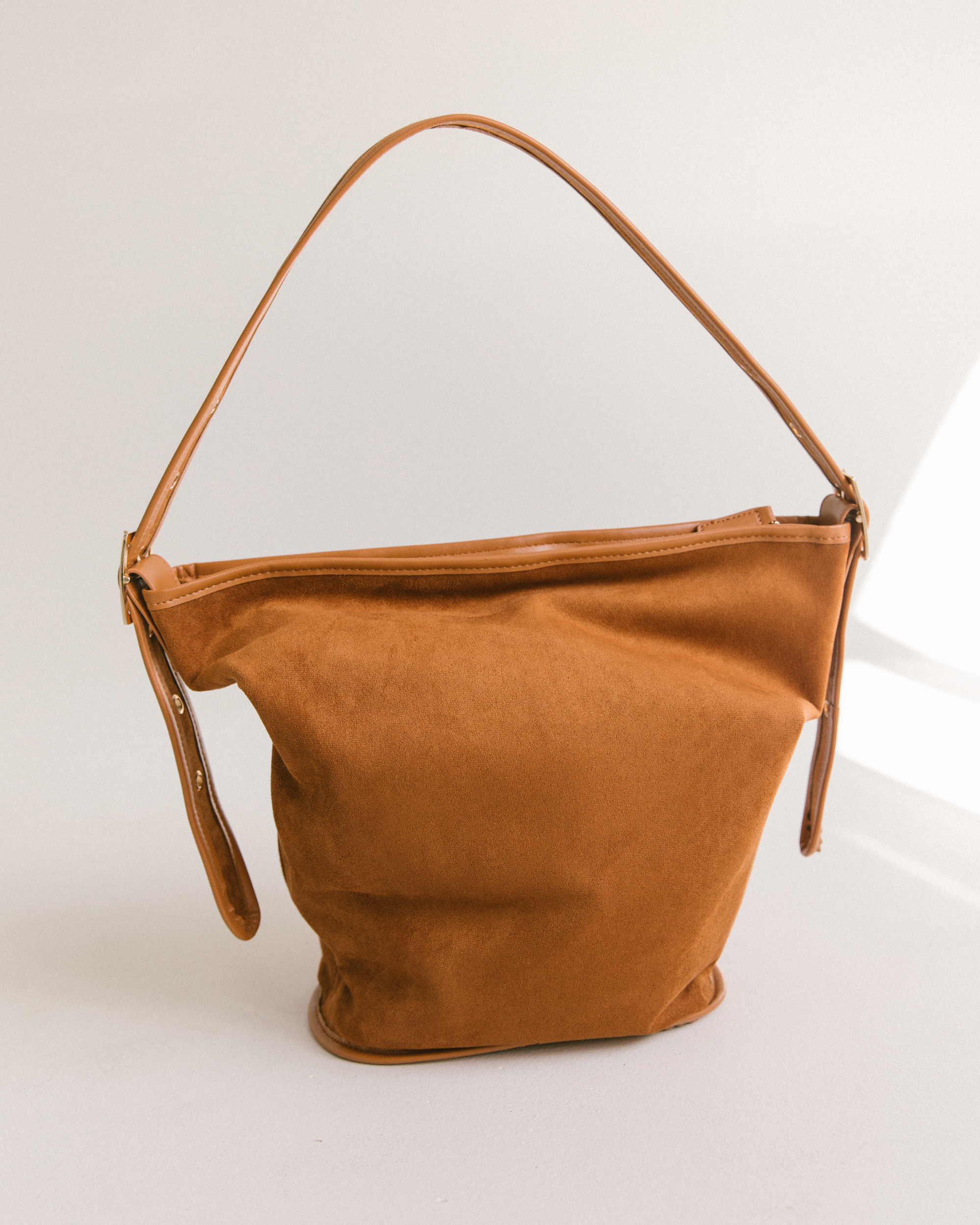 Brown suede handbag on a light gray background