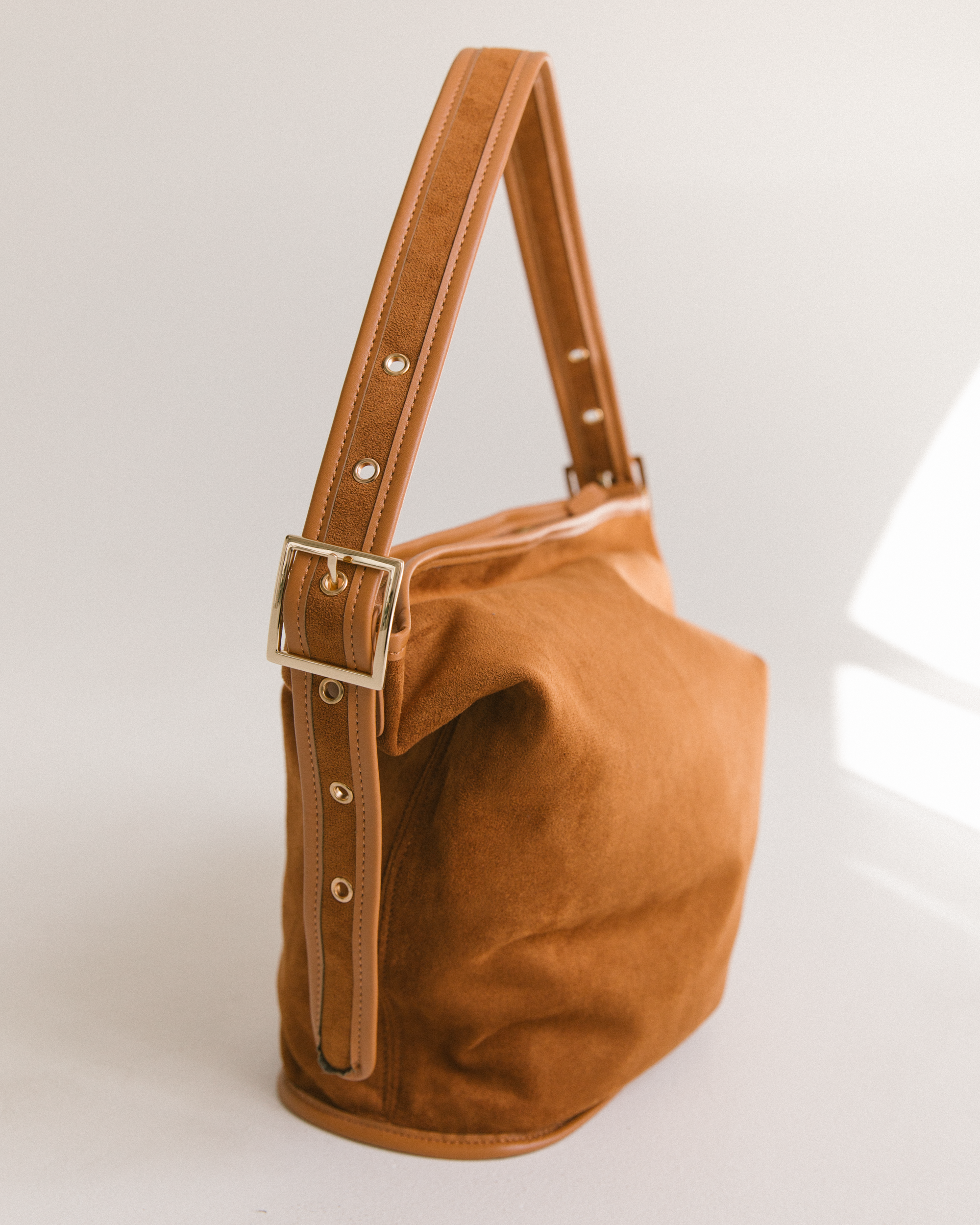 Close up of adjustable strap on honey coloured suede bucket bag.