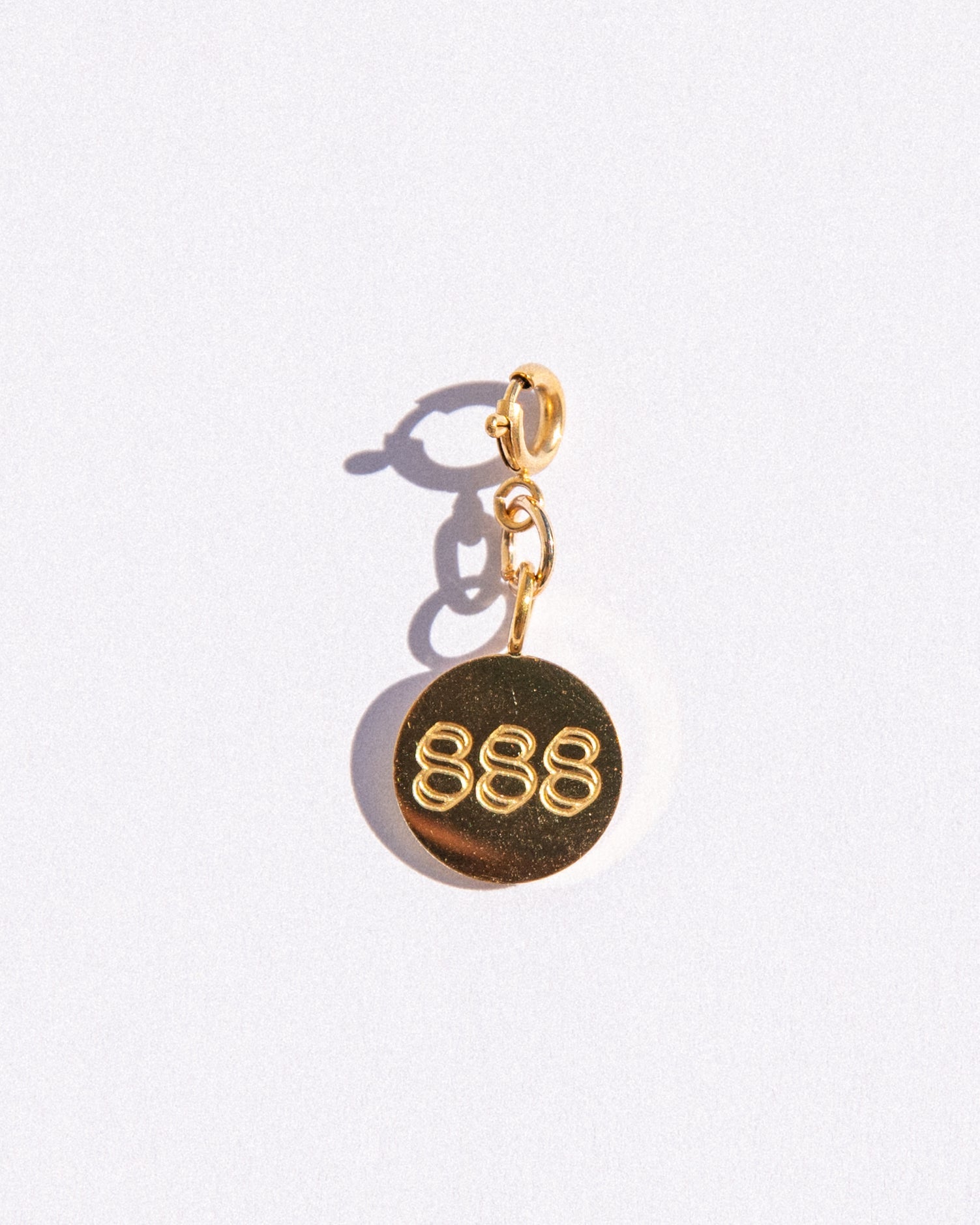 Gold circle charm with angel number '888' on a white background
