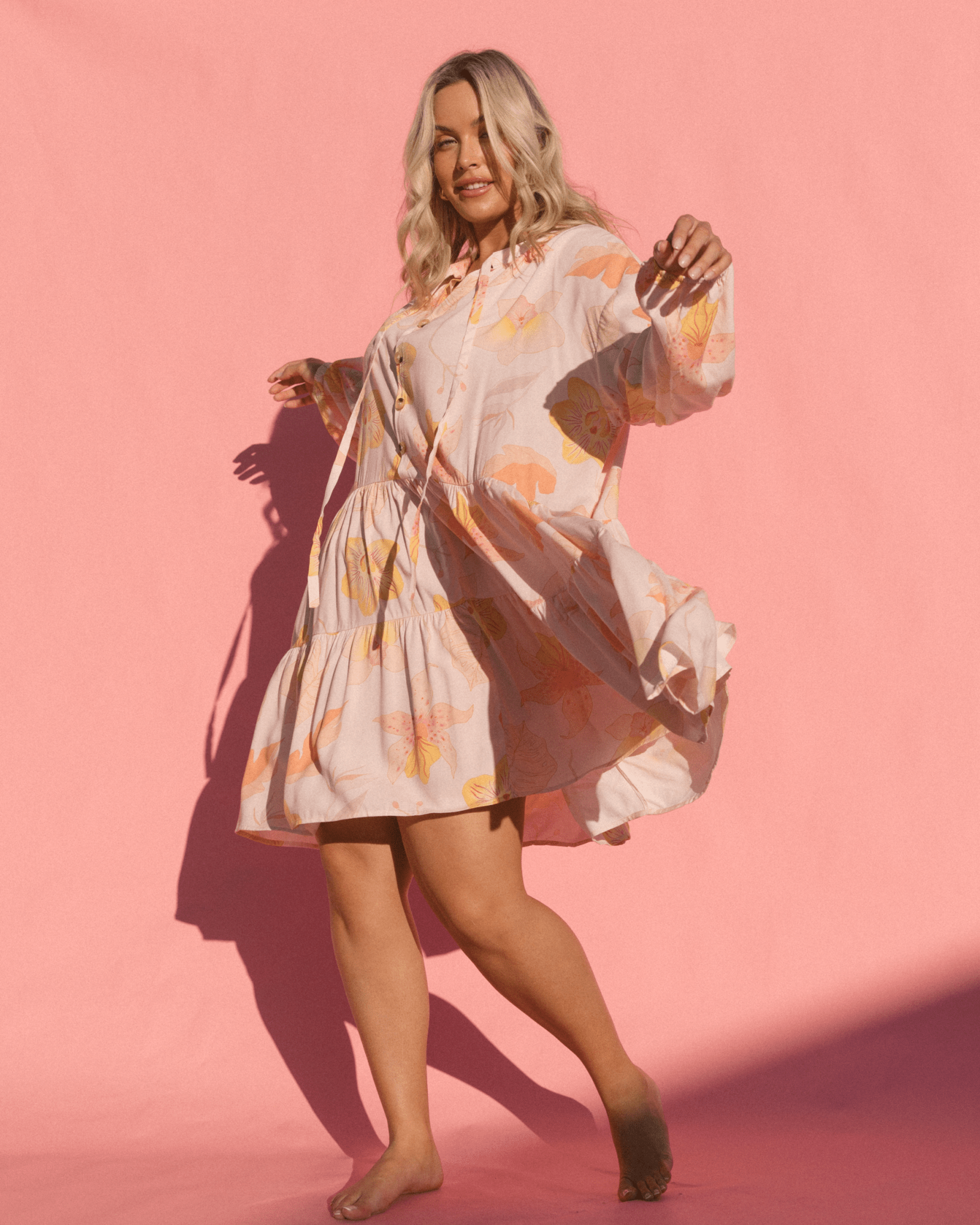 Woman wearing flowy, breathable floral dress in a light pink colour.
