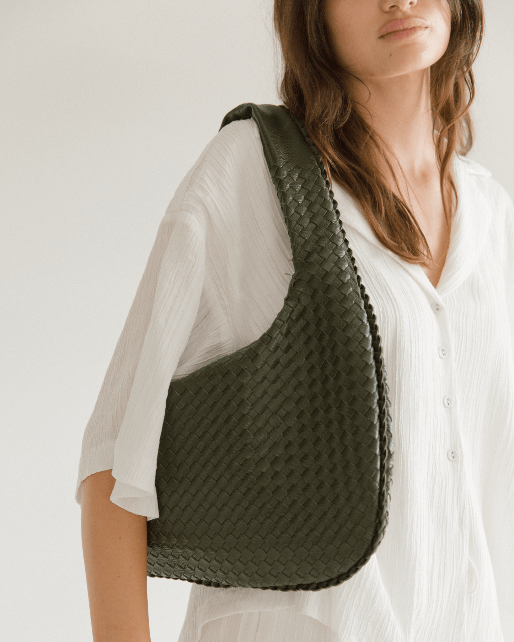Person wearing a green woven bag on a plain background
