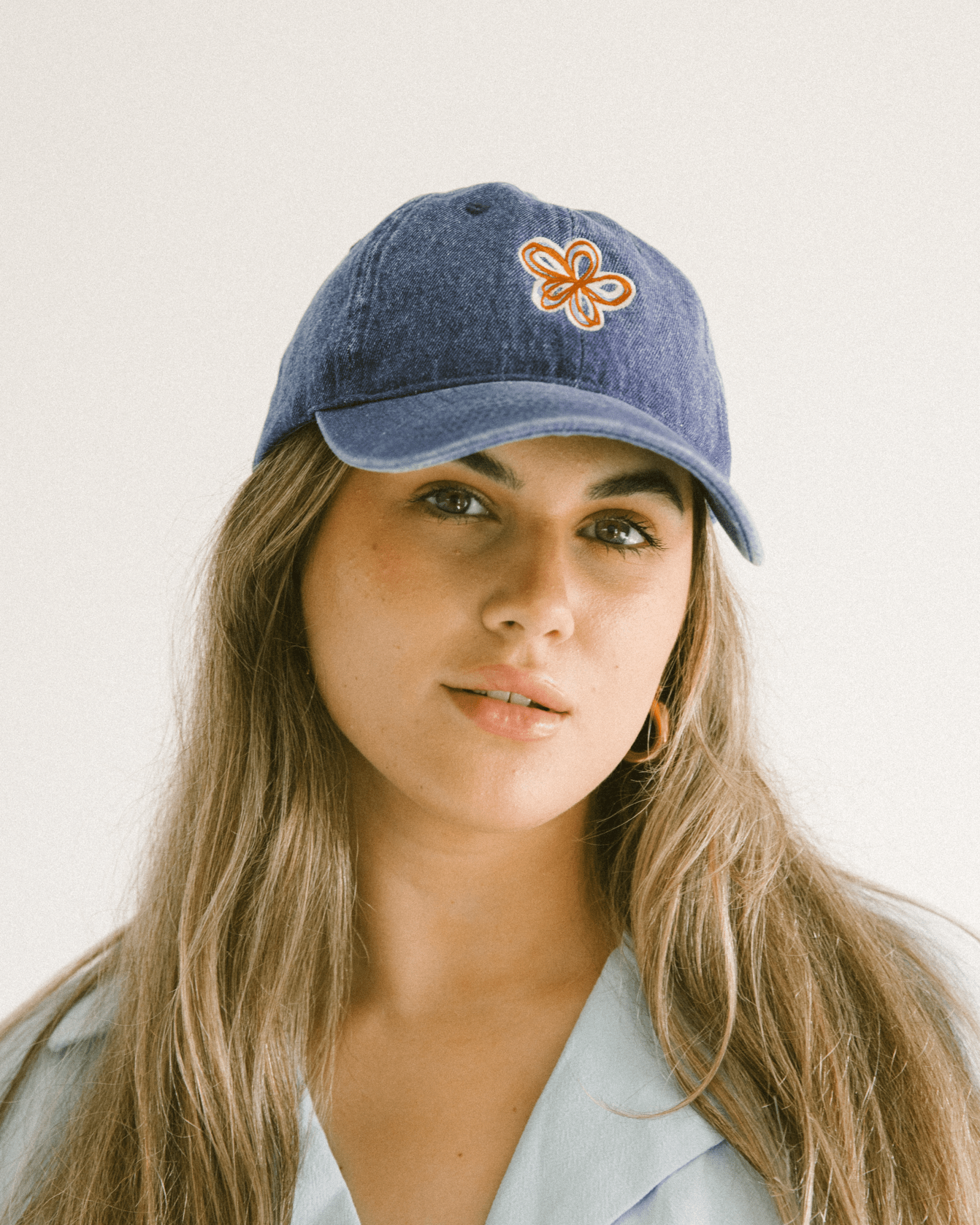 Women wearing denim cap with a multicoloured embroidered flower on the front.