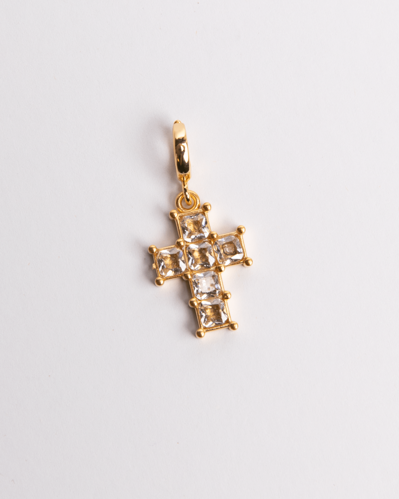 A gold-plated stainless steel diamond cross charm with a white background.
