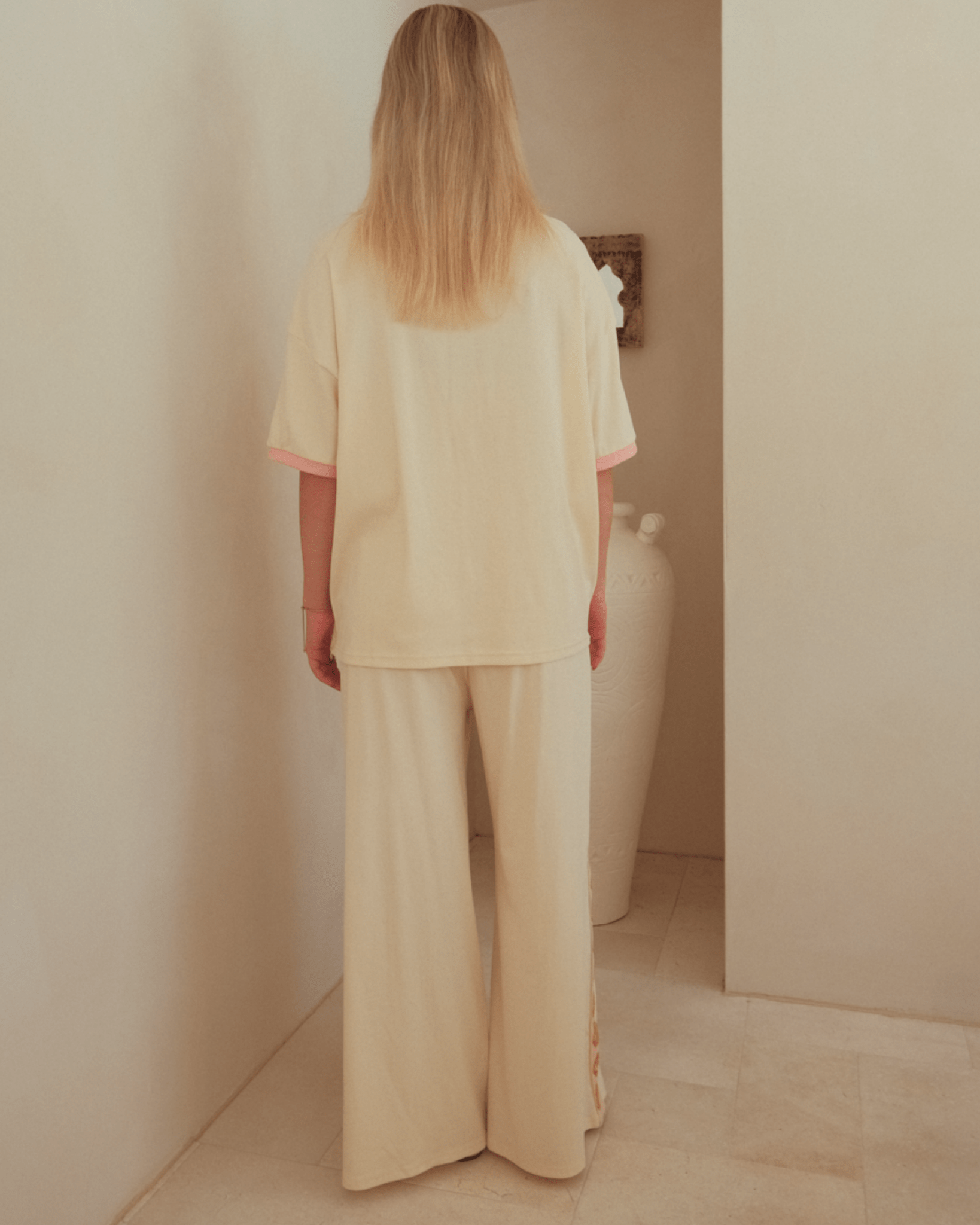 Woman wearing comfortable beige lounge set with oversized t-shirt and long pants.