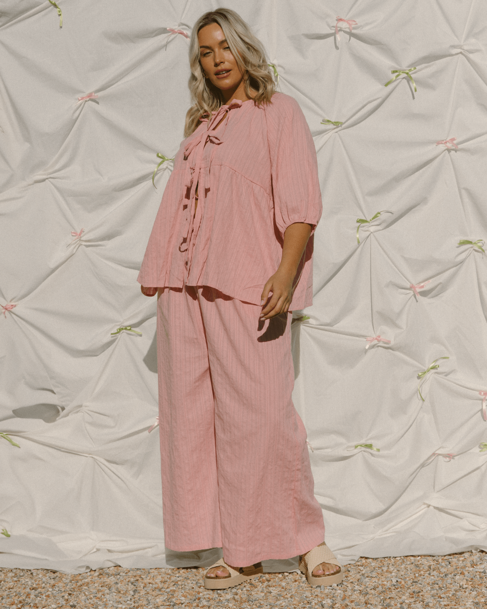 Woman wearing oversized pink co-ord set with tie-up reversible top.