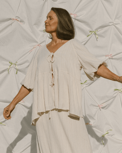Woman wearing cream coloured crepe oversized flowy shirt & long skirt set.