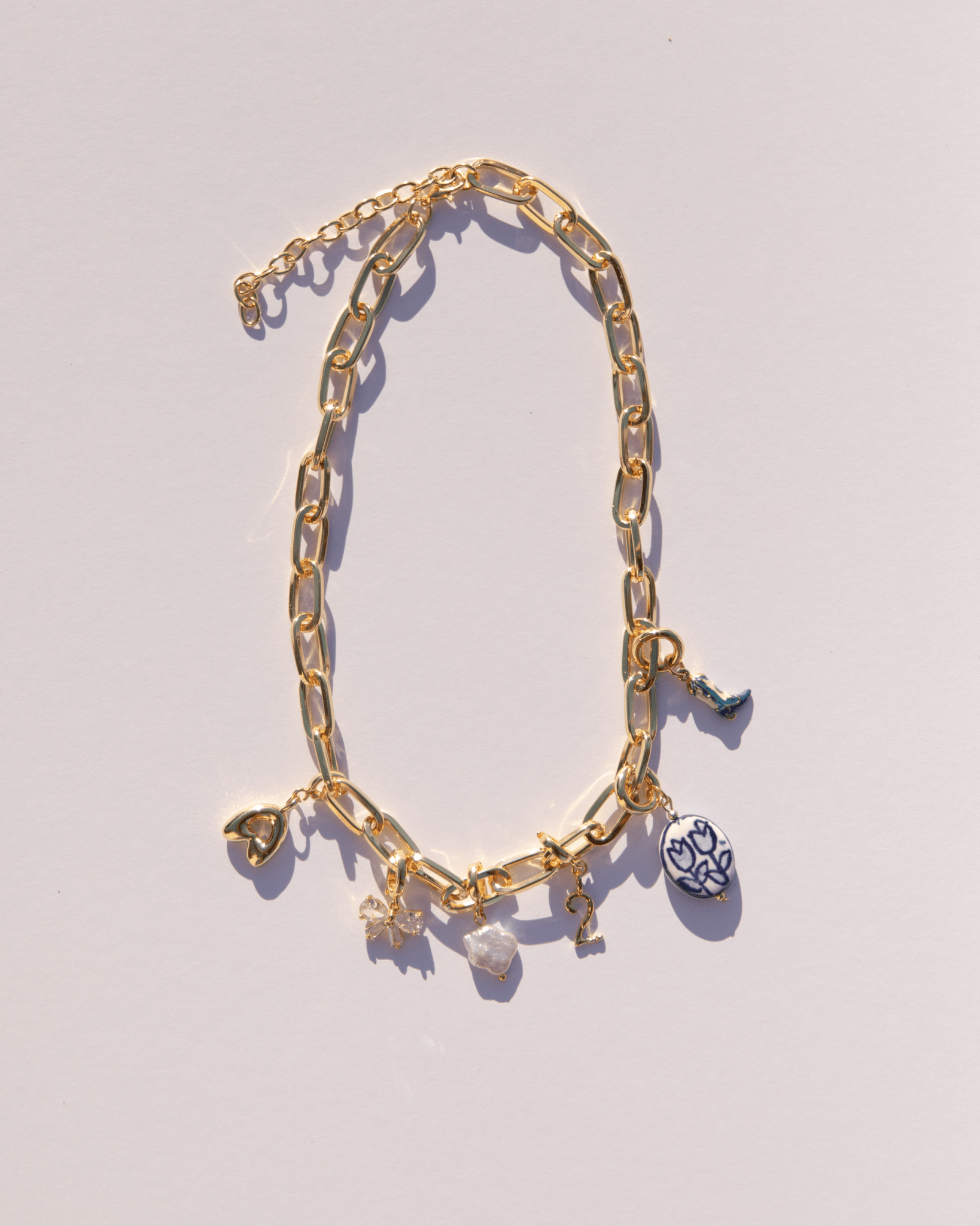 Gold paperclip chain necklace with an assortment of charms attached.