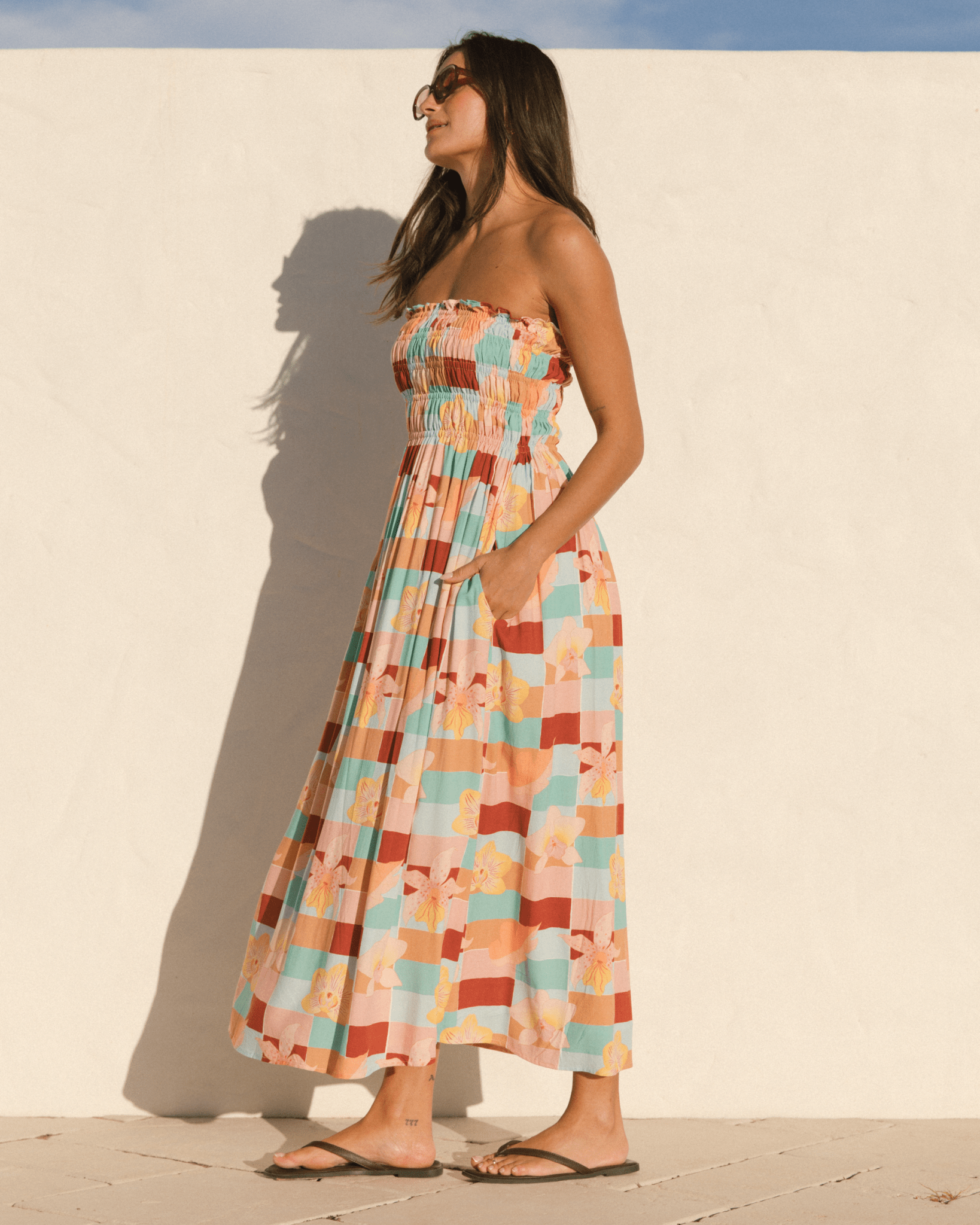 Woman wearing a colorful checkered dress against a white wall