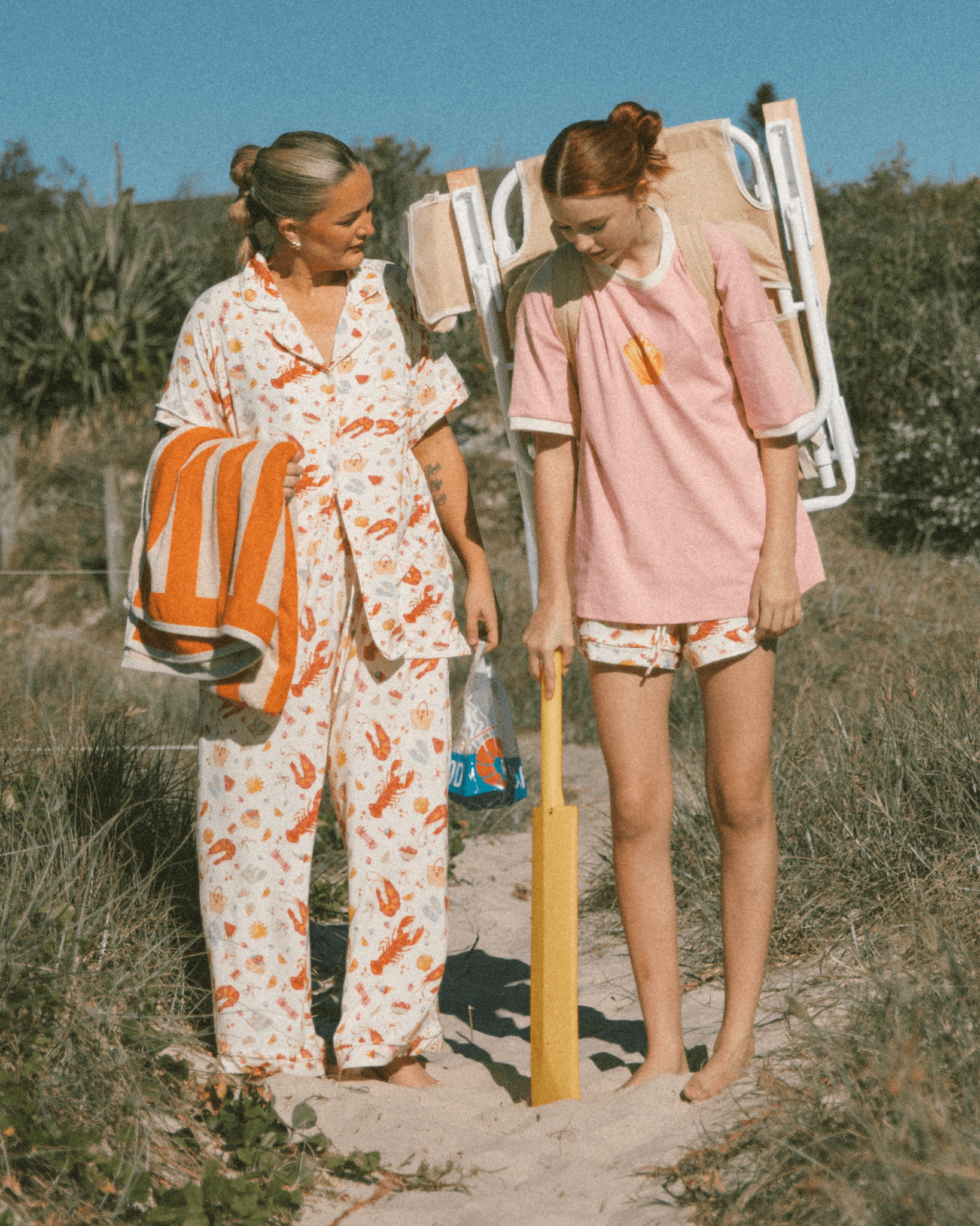 Two women in matching summer beach inspired pj's standing on the beach.