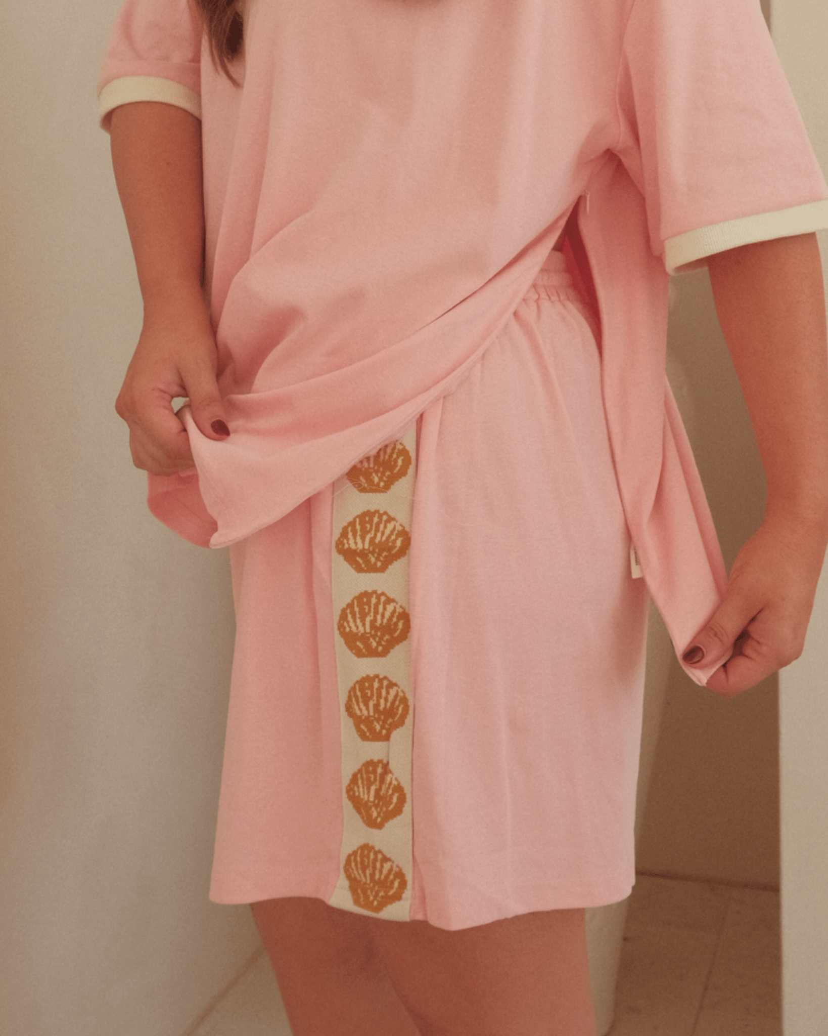 Woman showing breastfeeding side-zippers on oversized pink t-shirt.