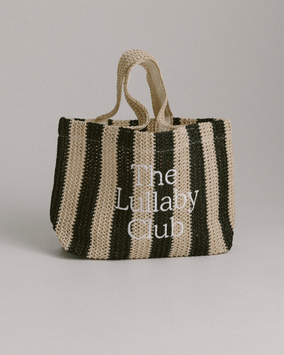 A black and natural raffia tote bag with 'The Lullaby Club' embroidered on the front.