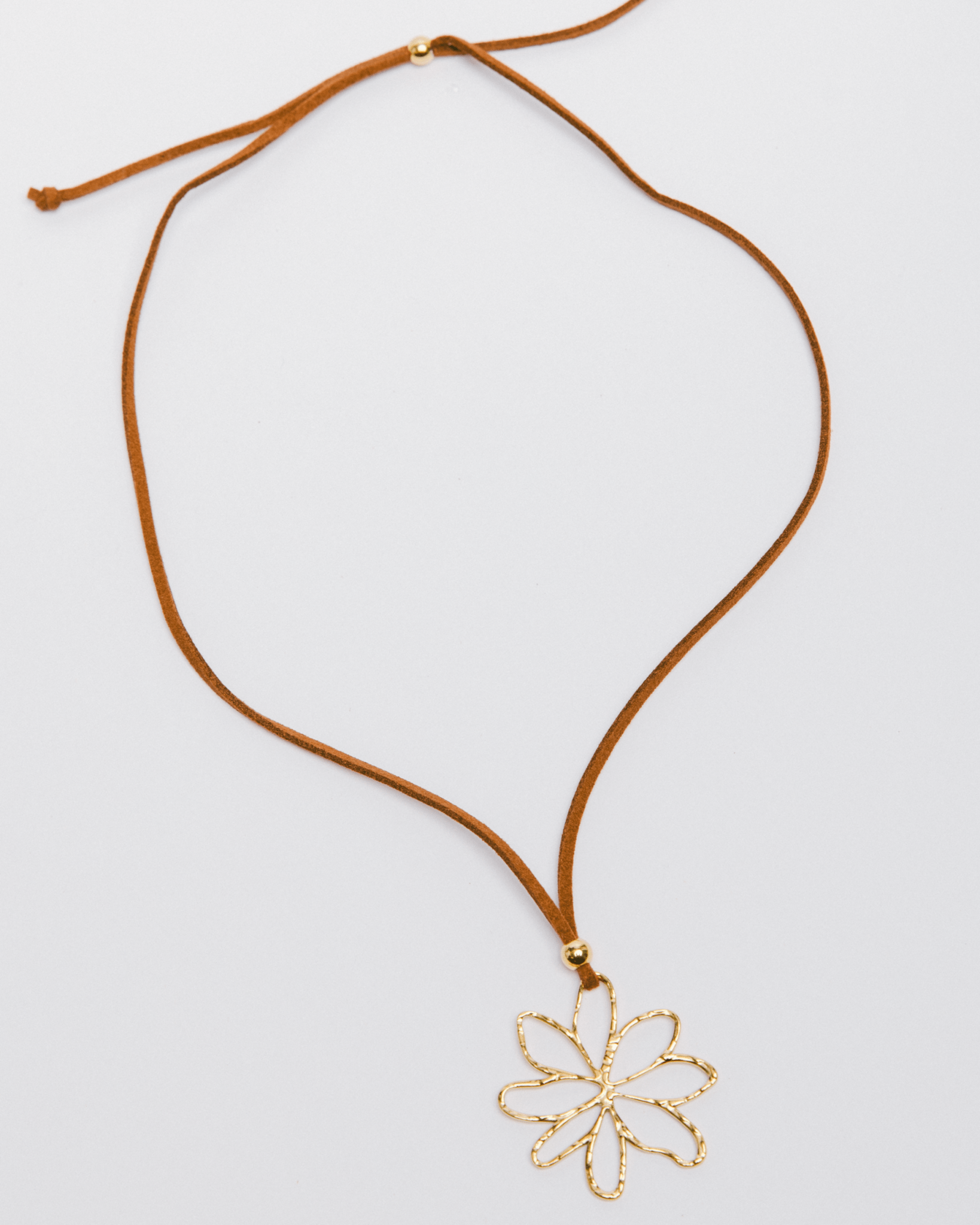 Necklace with a gold flower pendant on a light gray background