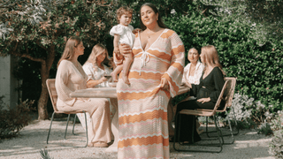 Mum with bub wearing knit pink wave dress in courtyard with friends wearing knit and neutral outfits