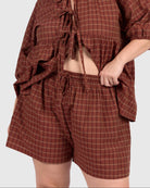 Woman wearing a brown plaid outfit on a white background