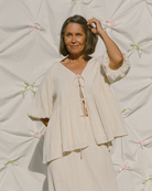 Woman wearing a beige outfit against a textured light background