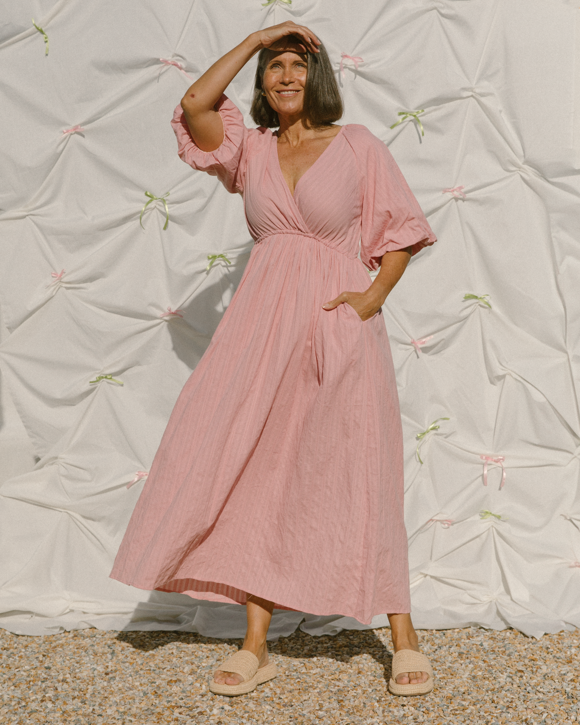Woman in pink breastfeeding friendly dress that is flowing in the wind. 