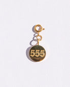 Gold circle charm with angel numbers '555' on a white background