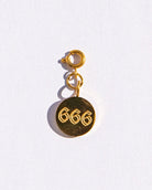 Gold circle charm with angel numbers '666' on a white background