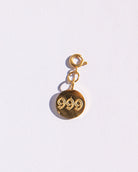 Circle gold charm with angel number '999' engraving on a white background