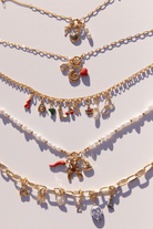 An assortment of stylish gold chain necklaces with charms attached.