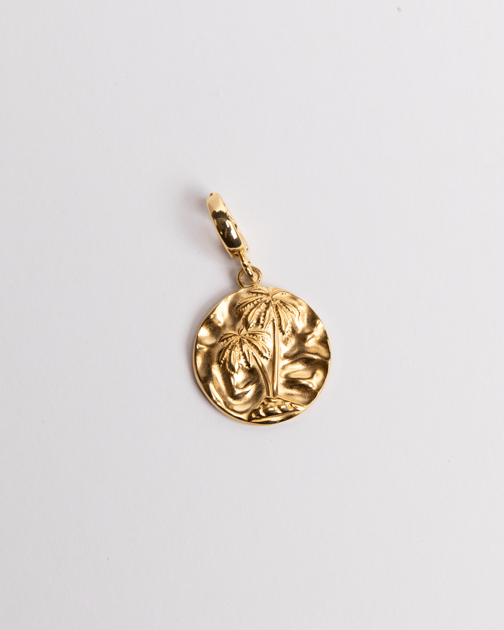 A gold-colored circular charm with a palm design, attached to a small loop for jewelry attachment.