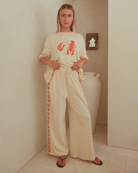 Woman wearing a cream-colored outfit with a red graphic design in a bathroom.