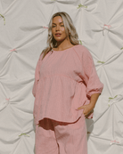 Woman wearing reversible pink top with breastfeeding hidden zippers. 