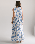 Woman wearing a long dress with blue floral pattern on a plain background