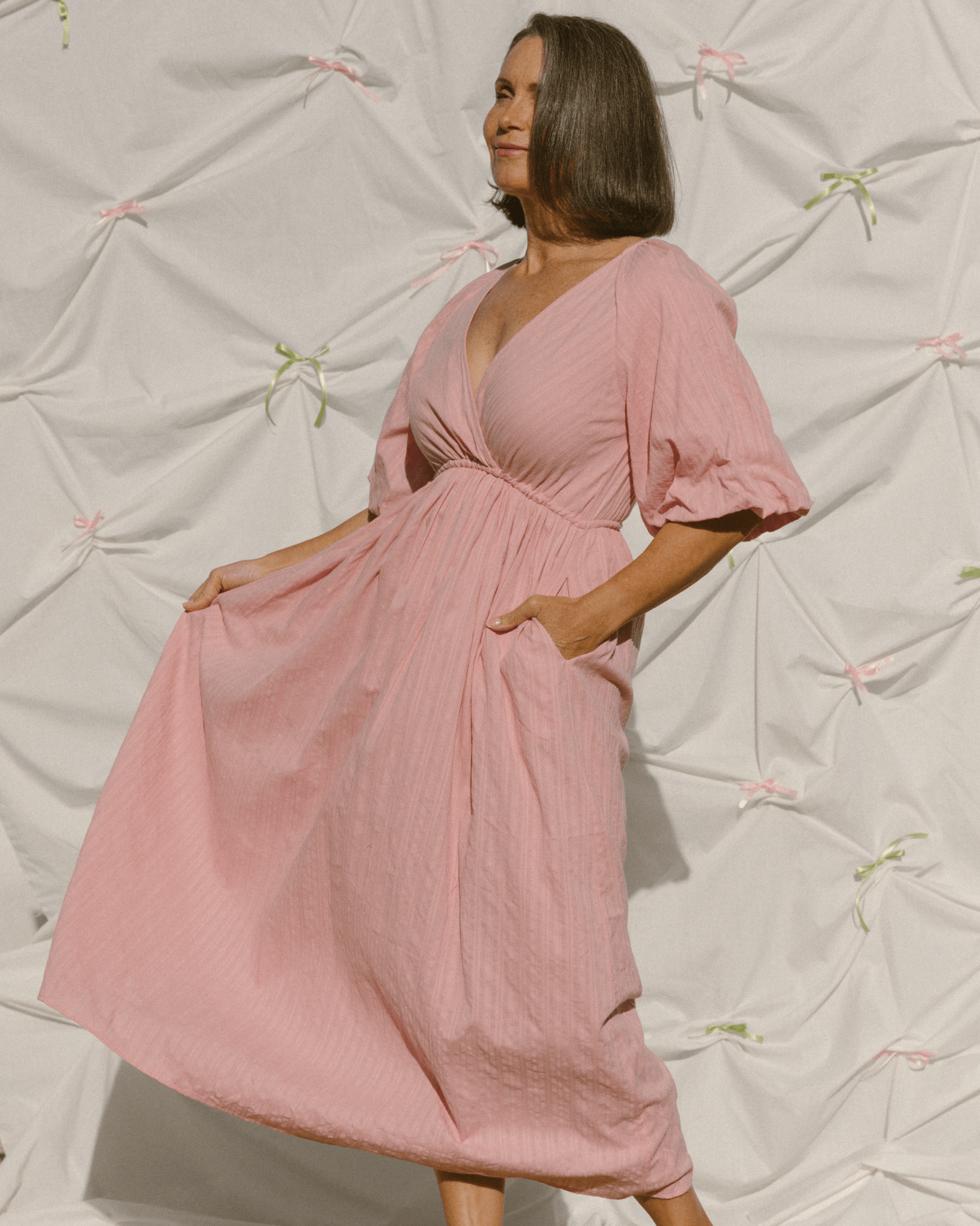 Woman wearing a pink dress against a textured white background