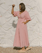 Woman wearing adjustable, breastfeeding friendly wrap dress with pockets in a blush pink colour. 