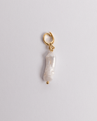 A white pearl charm with a gold-colored loop attachment, set against a white background.
