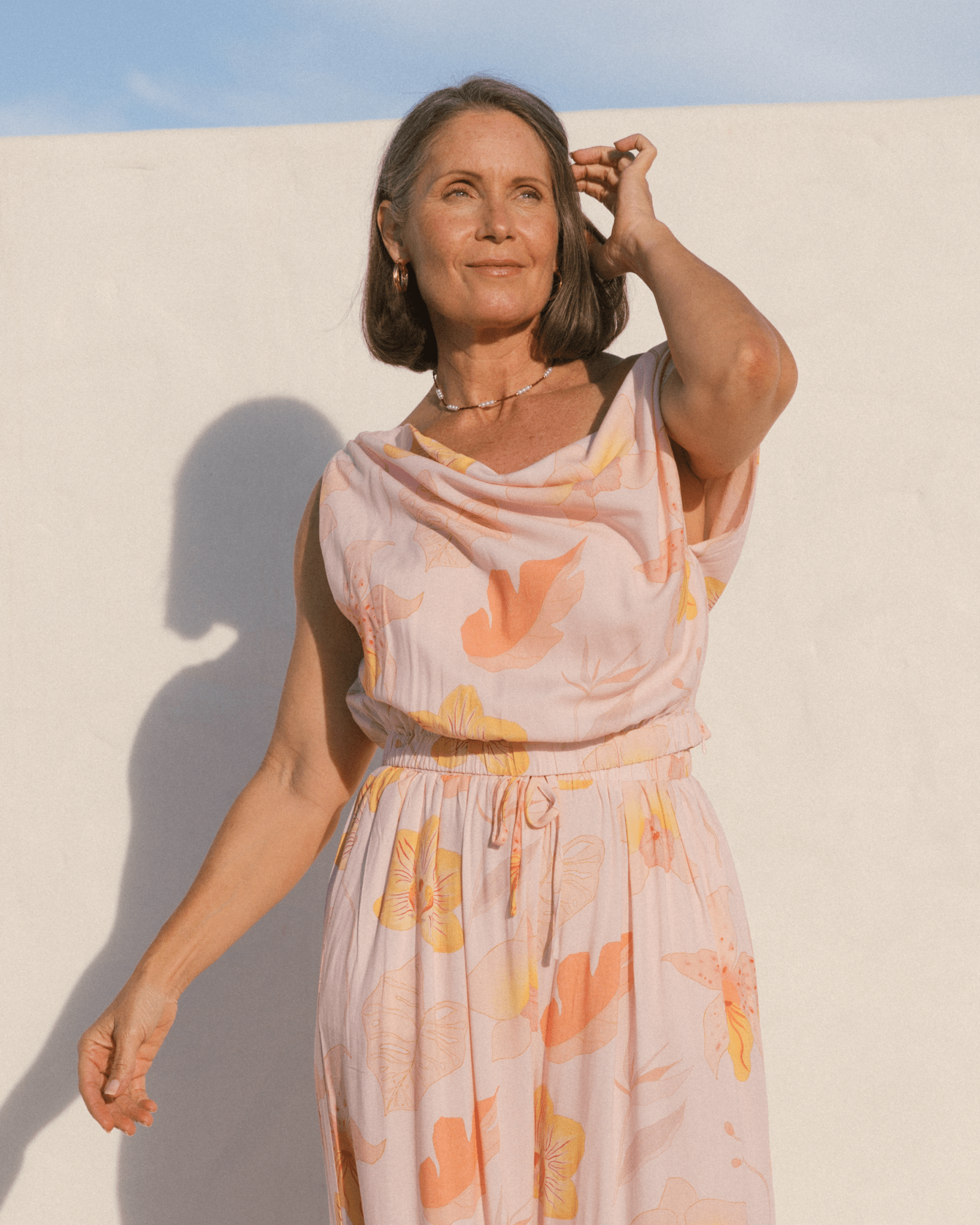 Woman wearing a casual floral spring time outfit, featuring a cowl neck crop top and elastic high-waisted pants. 