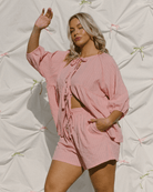 Woman wearing a pink reversible tie-up shirt with matching pink shorts.