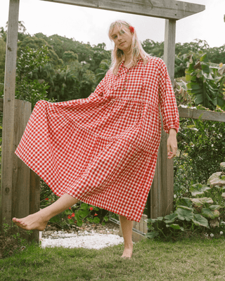 Woman in flowy postpartum-friendly maxi dress in red gingham