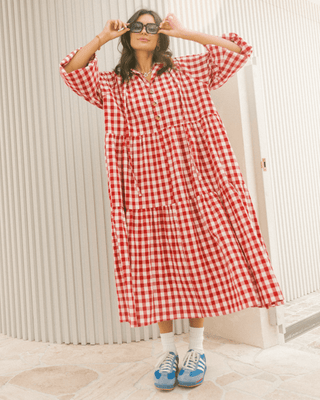 Woman in flowy postpartum-friendly maxi dress in red gingham