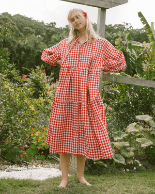 Woman in flowy postpartum-friendly maxi dress in red gingham