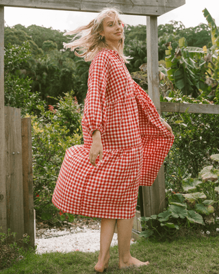 Woman in flowy postpartum-friendly maxi dress in red gingham