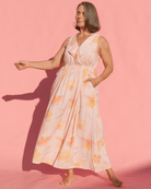Woman wearing light pink floral dress with side pockets & adjustable drawstring waist. 