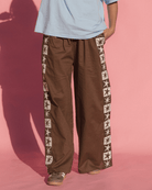 Person wearing brown pants with star patterns on a pink background