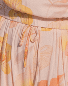 Close-up of a fabric with a floral pattern featuring orange, yellow, and beige colors.