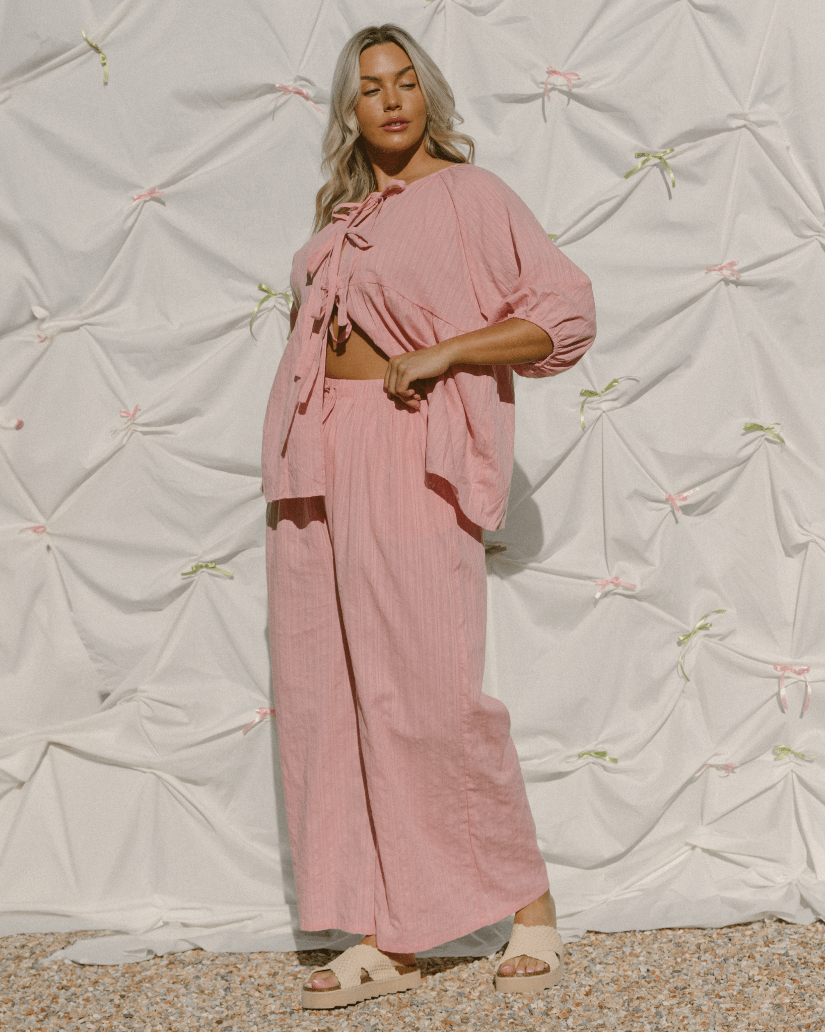 Woman wearing a pink stylish outfit with pink bows. 