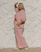 Woman wearing bump-friendly maternity lounge set in a blush pink colour. 