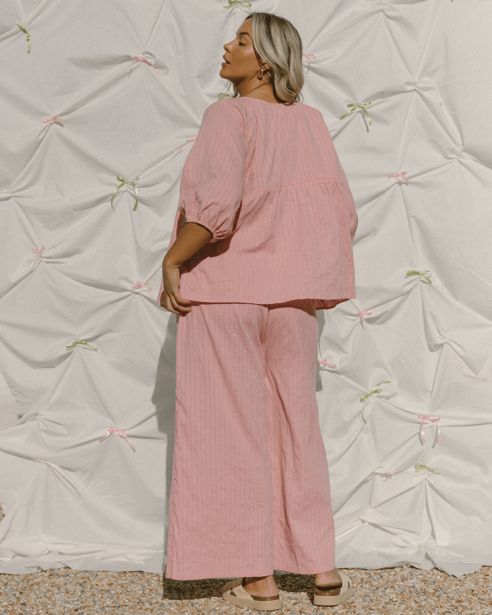 Woman wearing reversible blush pink top with matching long pants.