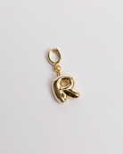 A gold-colored charm in the shape of the letter R with a secure clasp designed for attaching to necklaces or bracelets.