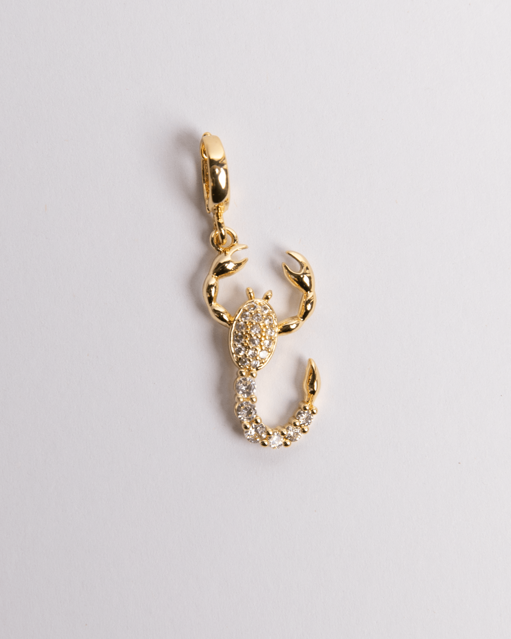 A gold-colored scorpion-shaped charm with a secure clasp for easy attachment, displayed against a white background.