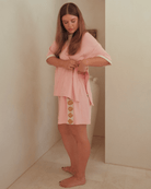Woman wearing oversized pink loungewear set with gold shell detailing. Featuring breastfeeding side-seam zipper on the tshirt. 
